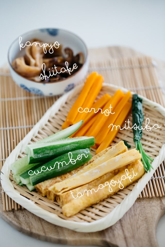 Futomaki sushi rolls ingredients on a bamboo tray - tamagoyaki, carrot, cucumber, mitsuba, and kanpyo