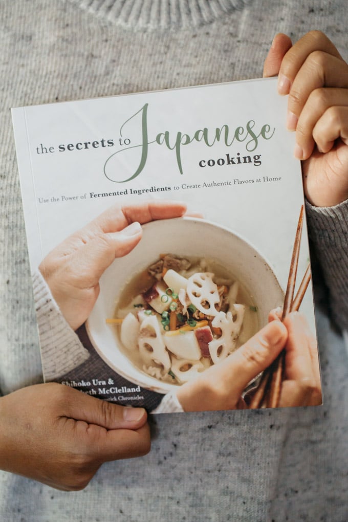 the author of "the secret to Japanese cooking" holding the book 