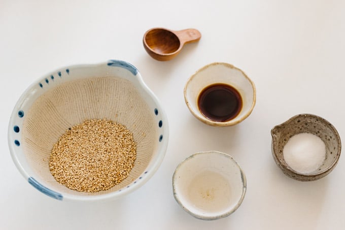 white sesame seeds in a Japanese mortar, soy sauce, dashi, and sugar in small bowls