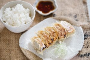 gyoza served on a plate with a bowl of rice and gyoza sauce