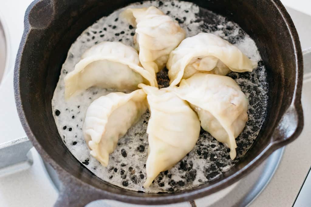 6 gyoza dumplings in a steel skillet
