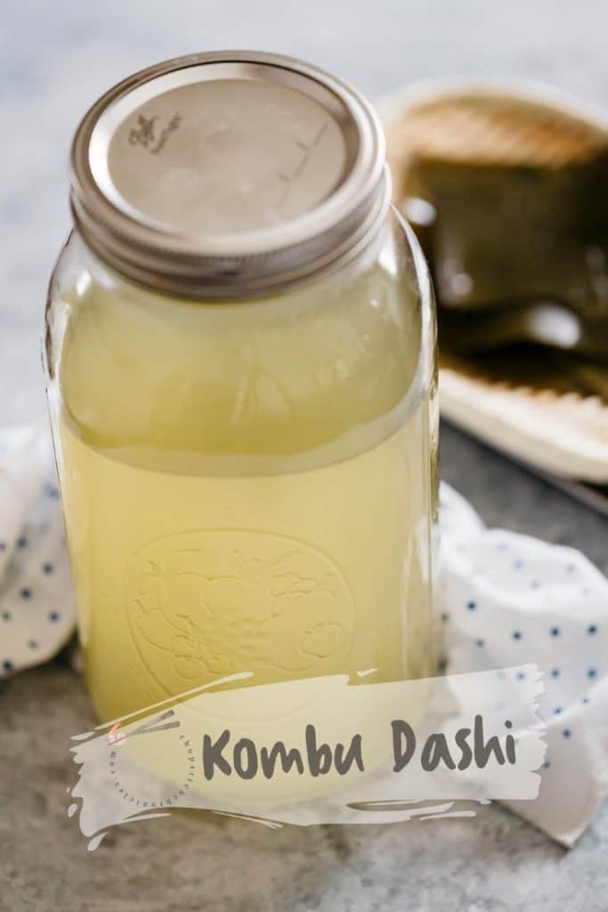 Kombu dashi in a large storing jar with kombu kelp on a bamboo tray in background