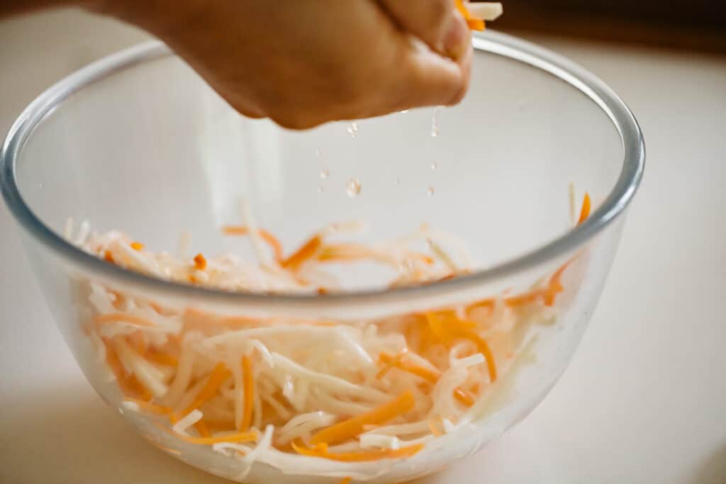 squeezing out moisture of daikon and carrot with two hands
