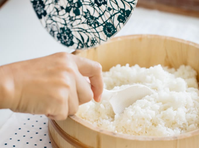 cooked rice in a wooden tub mixing rice and vinegar