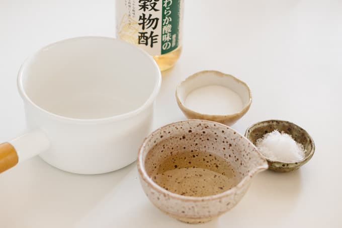 rice vinegar bottle, rice vinegar in a small bowl, sugar in a small bowl, and salt in a small bowl