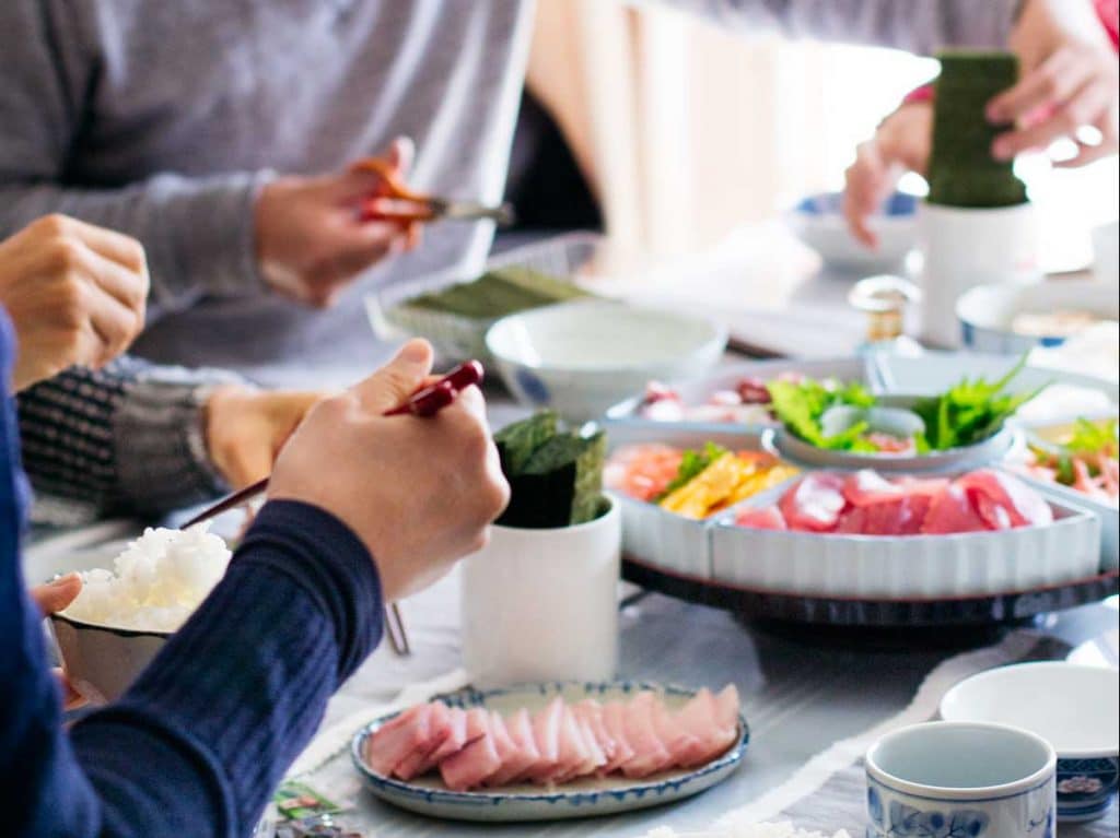 A family enjoying hand roll sushi making themselves at the table