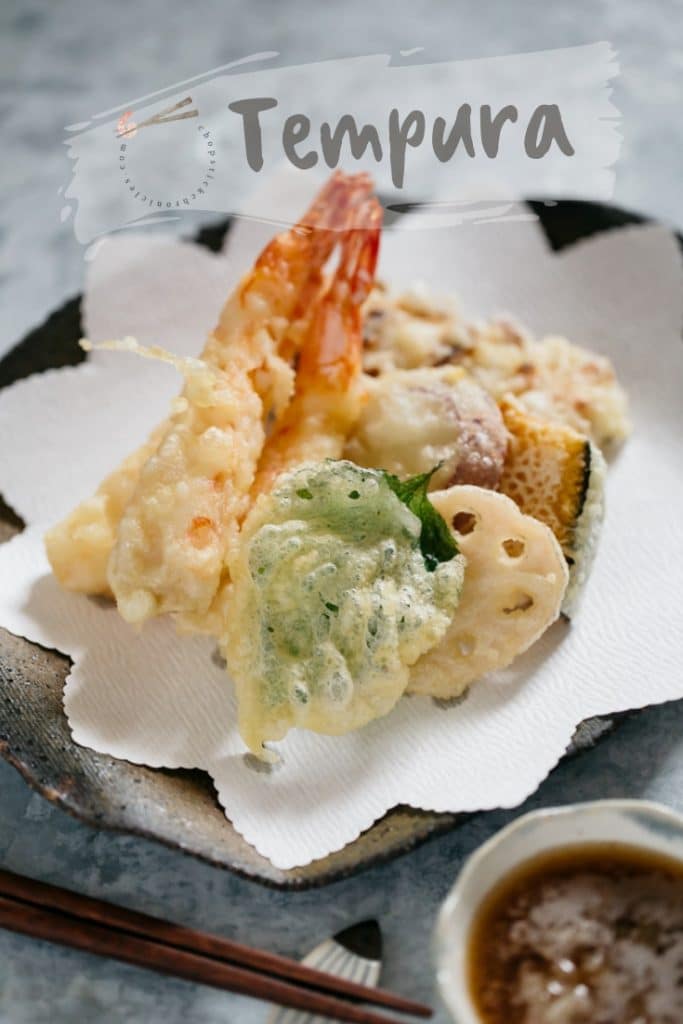 two prawn, shiso leaf, renkon, kabocha slice and chikuwa fish cake tempura on a plate