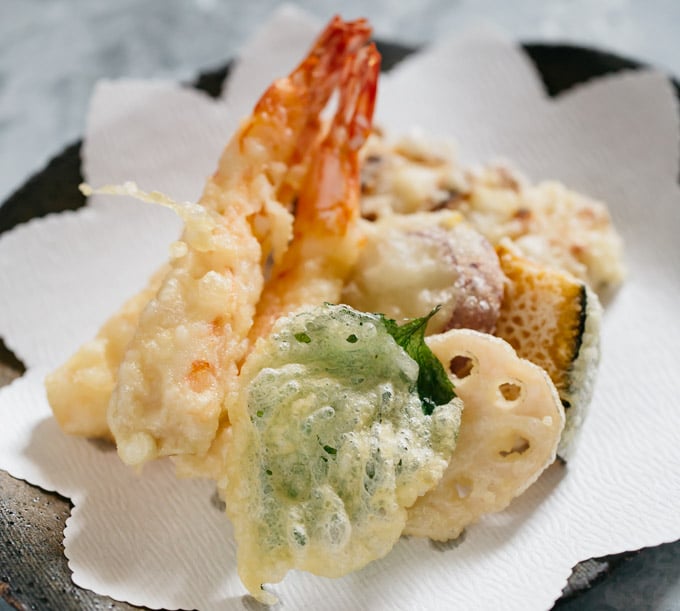 Two prawn tempura, shiso leaf, renkon, kabocha pumpkin and chikuwa tempura on a plate