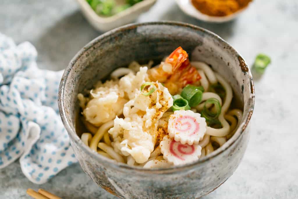 Tempura Udon served in a Japanese pottery bowl with two shrimp tempura