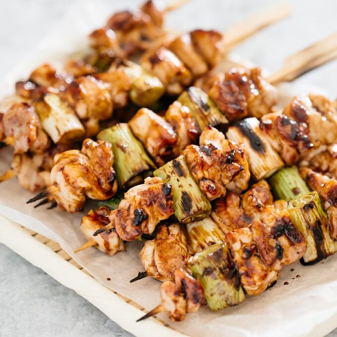 many skewers of Yakitori chicken are piled up on a bamboo tray