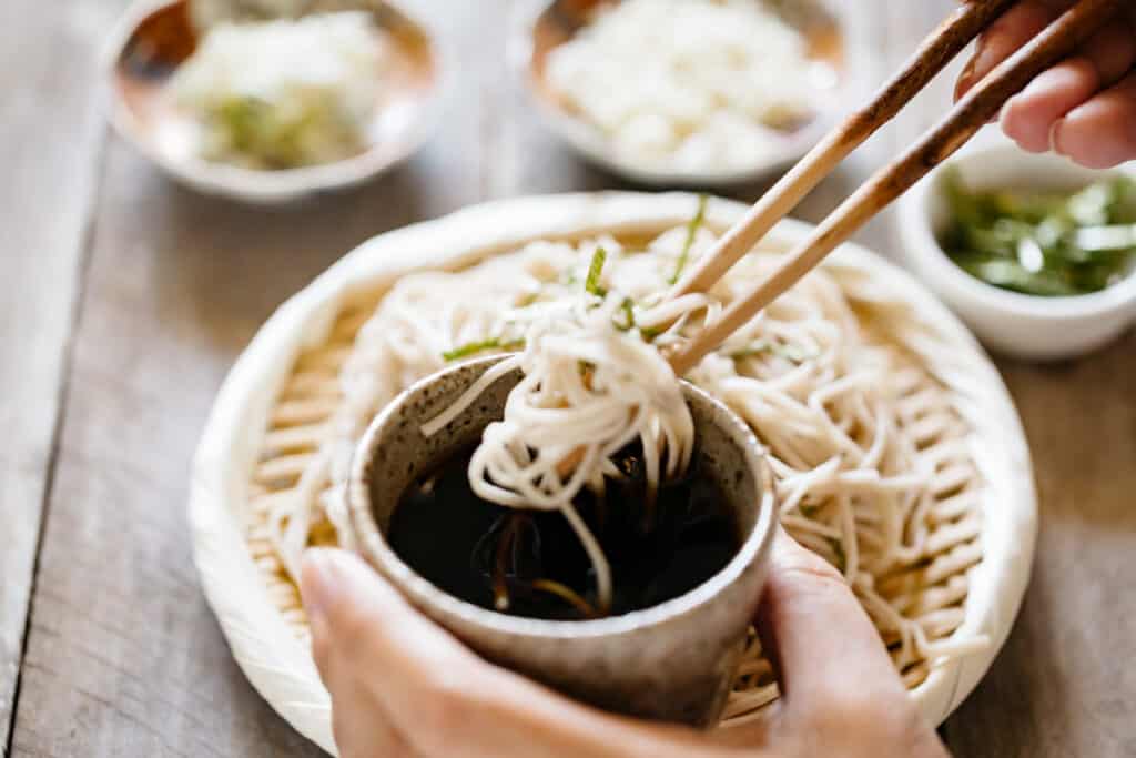  Zaru soba cold noodles dipped into a dipping sauce in a small cup 