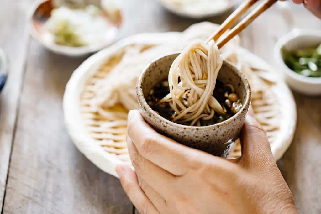 cold soba noodle dipped into a small cup of mentsuyu sauce