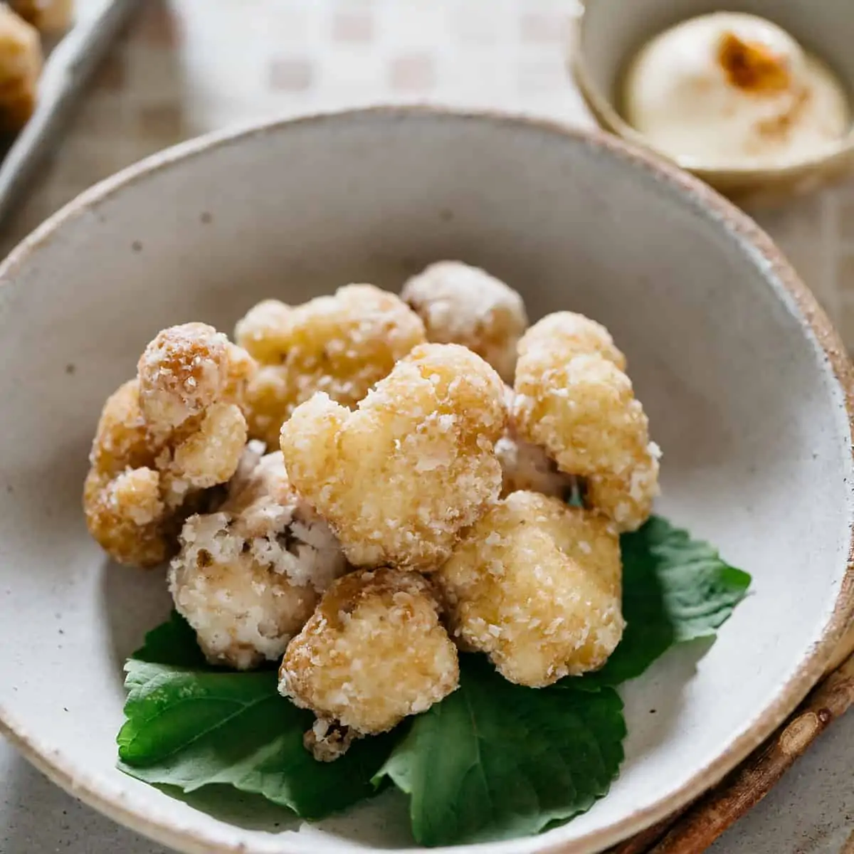 Fried cauliflower karaage is served with shiso leaves in a shallow bowl