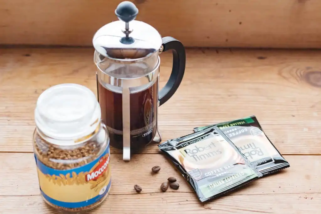 coffee plunger with coffee, coffee bags, coffee beans, and instant coffee jar