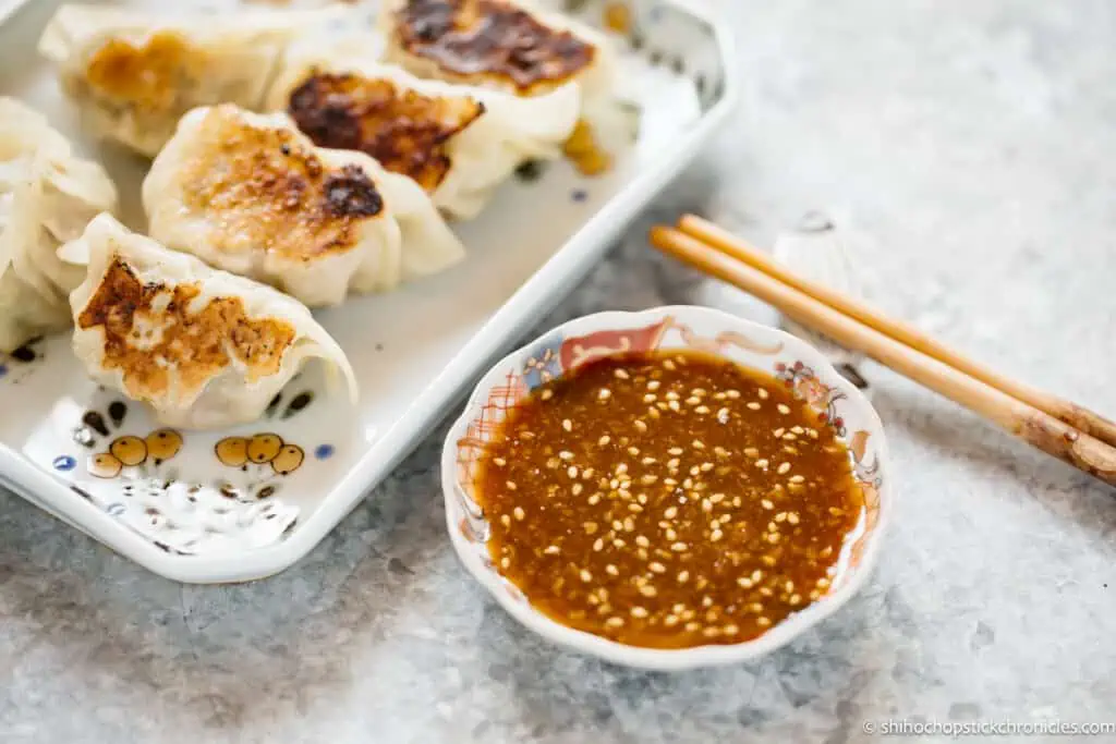 miso gyoza sauce in a small bowl with gyoza dumpling on a plate in background
