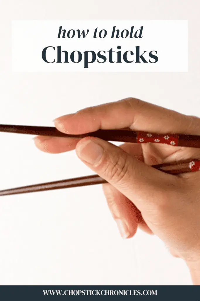 a hand holding a pair of chopsticks with text overlay for pinterest