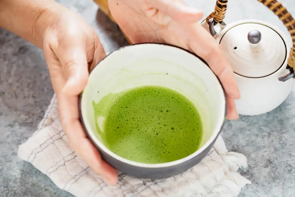 matcha served in a tea bowl with two hands on the side