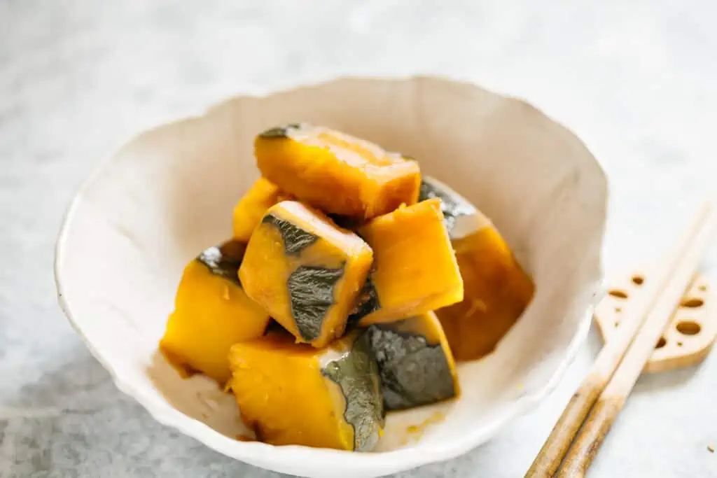 simmered kabocha squash served in a bowl with a pair of chopsticks