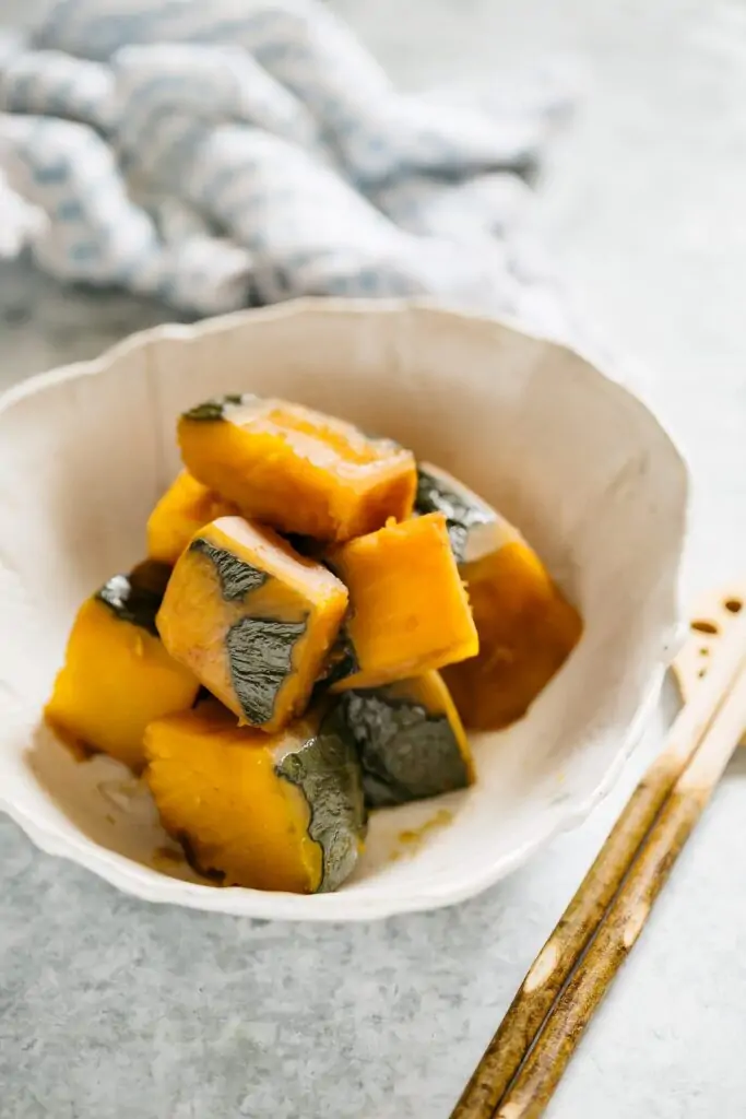 simmered Kabocha squash served in a Japanese pottery serving bowl with a pair of chopstick