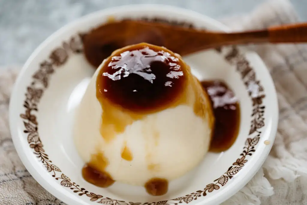 low carb creme caramel served on a plate with a wooden spoon