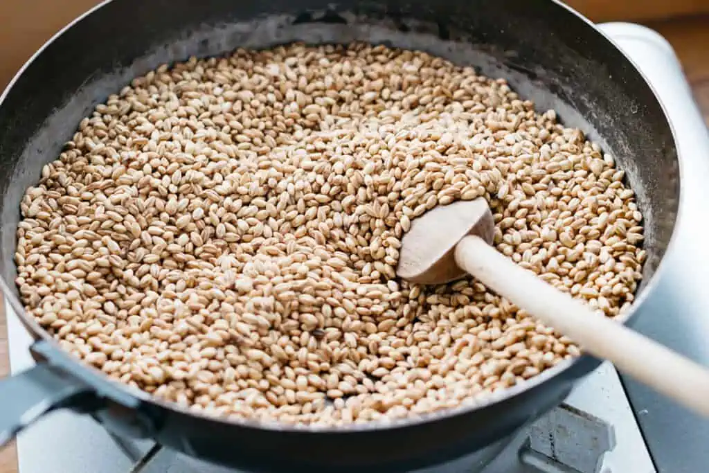 Barley grains being roasted in a frying pan