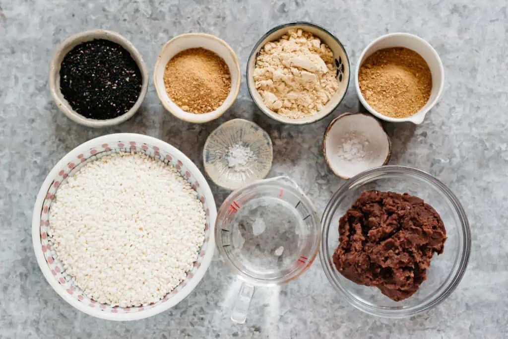 sweet rice, water, anko, black sesame seeds, kinako soybean powder, sugar, and salt on the kitchen bench