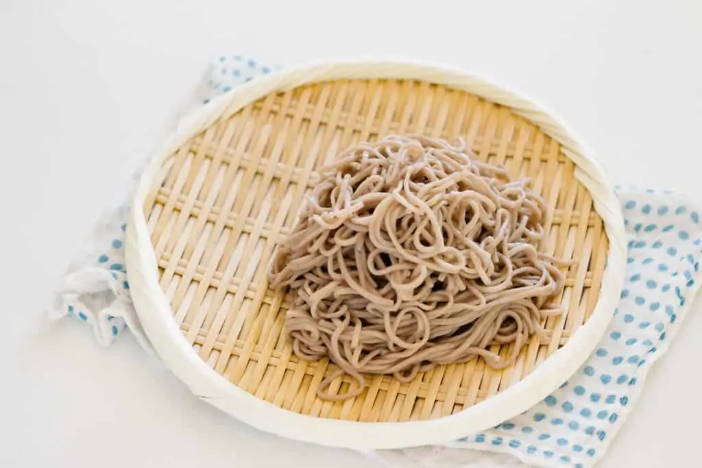 soba noodles cooked and served cold on a bamboo tray