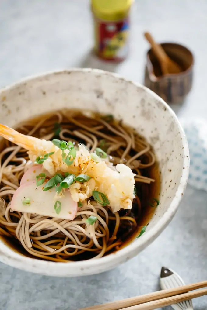 Toshikoshi soba noodle served in a noodle bowl with a tempura prawn and kamaboko fish cake with soup
