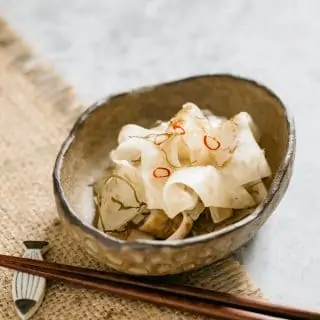 Pickled daikon served in an oval bowl with a pair of chopstick