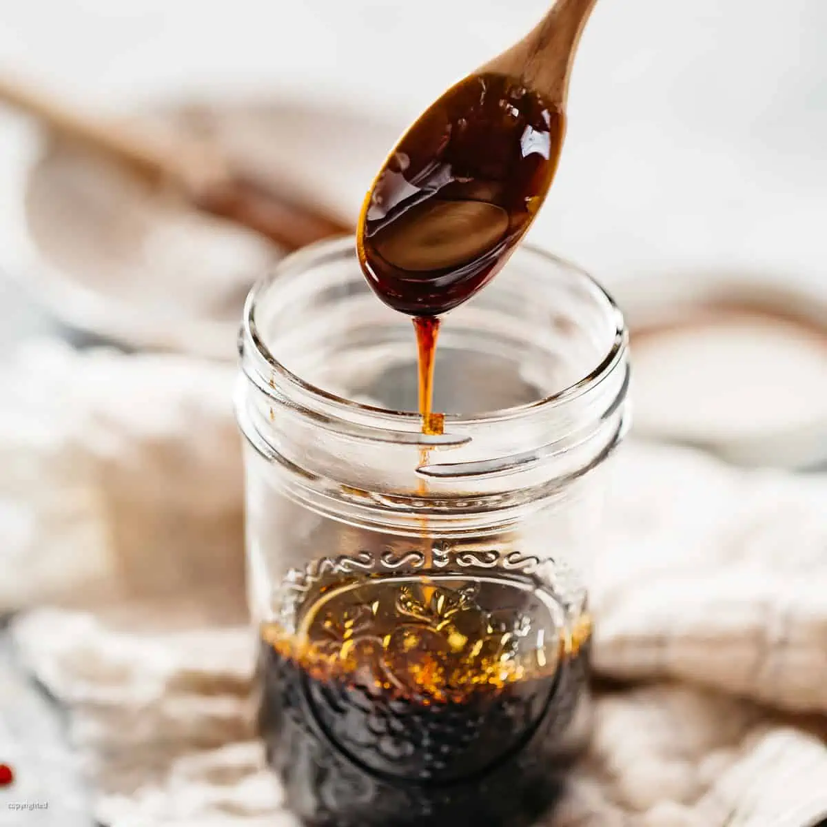 Unagi sauce in a glass jar with a wooden spoon