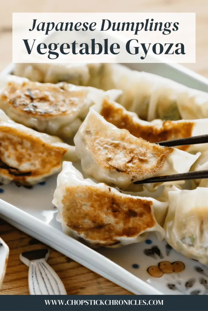 vegetable gyoza served on a rectangle plate with a pair of chopsticks with text overlay for pinterest